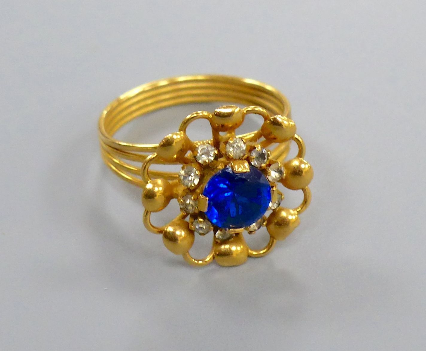 A Middle Eastern yellow metal ring, set with a blue and white paste stones, size O/P, gross 4.8 grams.